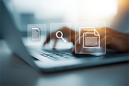 Fingers on a laptop keyboard with document icons floating above